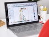 Oprogramowanie Bernina V9 Creator na laptopie, wyświetlające projekt haftu z kolorowymi kwiatami na białym tle. Widziane z przodu, na biurku z akcesoriami do szycia w tle, w tym nożyczkami i szpulkami nici.