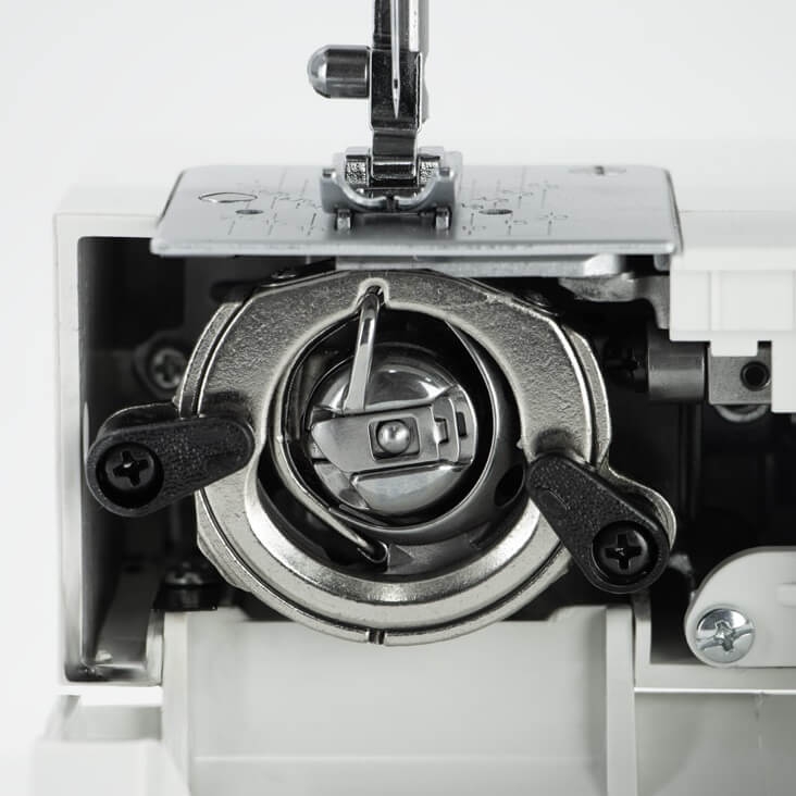 Zbliżenie na element maszyny do szycia TEXI GOLD z silnikiem servo, ukazujące szpulownik. Metalowa osłona i dwa czarne uchwyty. Widoczny mechanizm na tle białej obudowy, z wyraźnymi detalami konstrukcyjnymi.