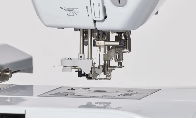 Hafciarka Brother F540E w zbliżeniu na mechanizm szycia. Widoczna igła, stopka oraz elementy robocze maszyny na białym tle. Maszyna ma metalowe detale i czytelne oznaczenia numeryczne na obudowie.
