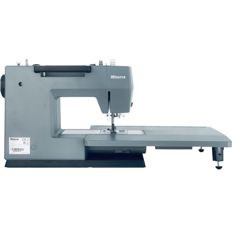 Maszyna do szycia Minerva HS1100 Heavy Duty w szarym kolorze, widok z boku. Posiada duży stół roboczy, igłę i mechanizm szyjący na widoku, z czytelnym logo Minerva. Produkt stoi na czarnej podstawie, idealny do szycia ciężkich materiałów.