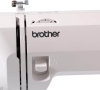 Maszyna do szycia Brother XN1700 w kolorze białym, z wyraźnym logo brother. Widoczna pokrętło do regulacji oraz elementy mechaniczne. Ujęcie z boku, co podkreśla detale konstrukcji. Idealna do użytku domowego i hobbystycznego.