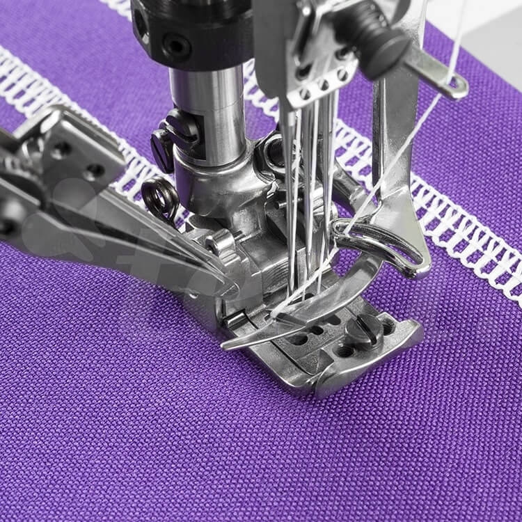 Renderka TEXI TRECCIA C MATIC PREMIUM z interlokiem 3-igłowym, zbliżenie na stopkę i igły, metalowa konstrukcja, działająca na fioletowym materiale z widocznym wzorem. Elektromagnetyczne obcinanie nici, precyzyjne detale maszyny.