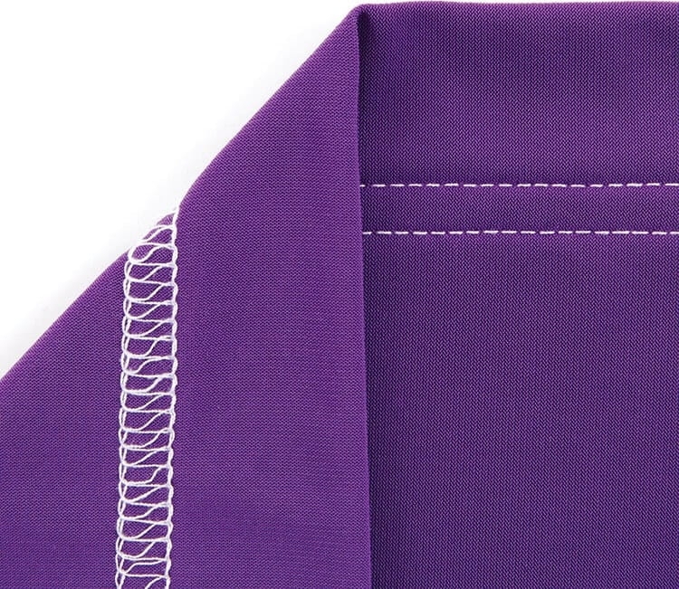 Renderka TEXI TRECCIA C MATIC PREMIUM z widocznym fragmentem materiału w kolorze purpurowym, wykończonym 3-igłowym ściegiem interlok. Zbliżenie na detal szwu oraz gładką fakturę tkaniny.