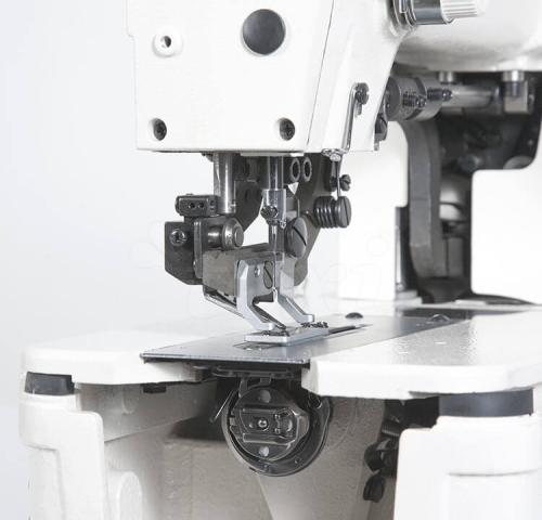 Dziurkarka TEXI 781 SERVO PREMIUM z obcinaniem nici, widok z boku na stopkę i igłę, metalowe elementy, biała obudowa, widoczny mechanizm dolny z szpulą. Prosta, ergonomiczna konstrukcja, idealna do szycia bielizny.