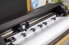 Ploter tnący Silhouette Cameo Pro MK II w kolorze czarnym, widok z góry. Na zdjęciu widoczne są detale mechanizmu tnącego oraz rolki podtrzymujące materiał. Tło jest neutralne, co podkreśla produkt.