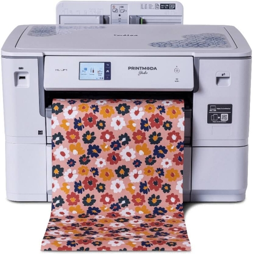 Drukarka Brother HL-JF1 PrintModa Studio w kolorze białym, z wyświetlaczem dotykowym, z rolką papieru w różowe kwiaty na jasnym tle, wydobywająca wzór. Produkt stoi na płaskiej powierzchni, z widocznym logo na obudowie.