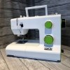 Maszyna do szycia PFAFF SMARTER 140S w kolorze białym z zielonymi pokrętłami, stojąca w ujęciu z boku. Widoczny mechanizm szycia, numer modelu 140S oraz logo smarter by PFAFF na obudowie.
