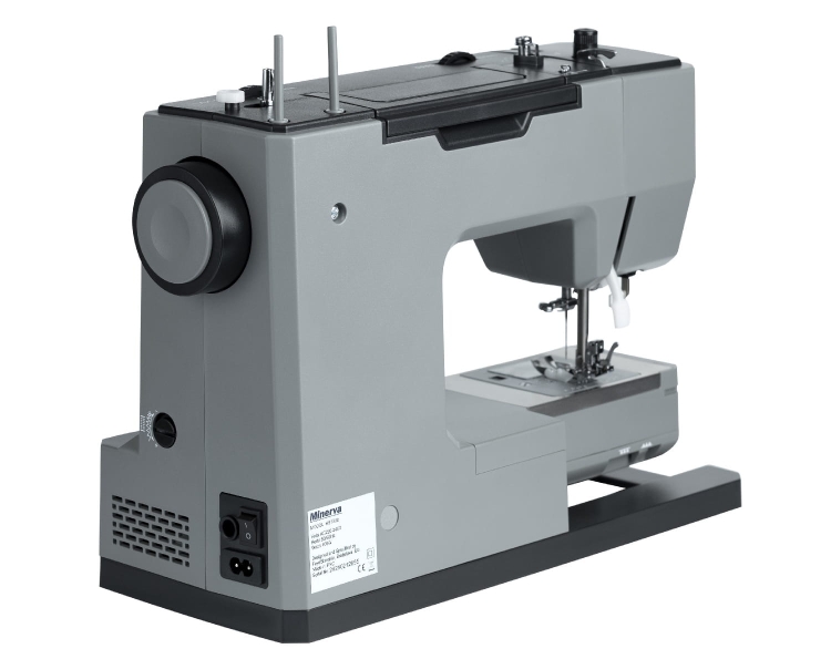 Maszyna do szycia Minerva HS1000 w kolorze szarym, mechaniczna, z widocznym uchwytem do szycia oraz wbudowanym stoperem. Ujęcie z boku, ukazujące panel sterujący, igłę i stopkę. Stojąca na ciemnej podstawie, w prostym tle.