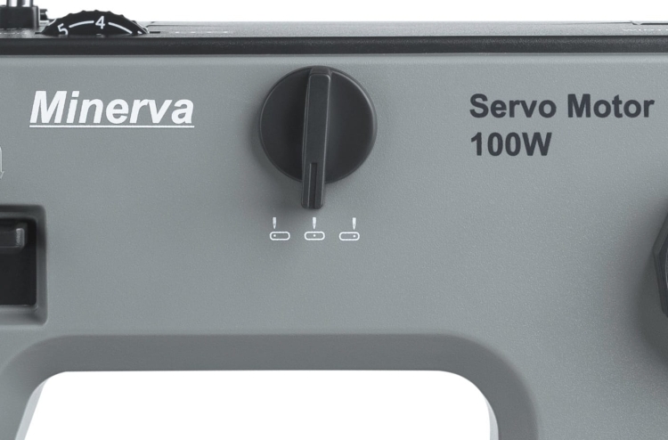 Maszyna do szycia Minerva HS1000 w kolorze szarym, z widocznym pokrętłem regulacji i wskaźnikiem mocy 100W. Ujęcie frontalne, ukazujące detale panelu sterującego z logo marki.