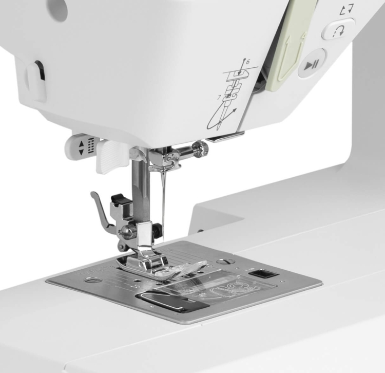 Maszyna do szycia Minerva SmartDecor w kolorze białym z widoczną stopką, metalowym blatem oraz przyciskami do obsługi. Ujęcie zbliżeniowe na igłę i mechanizm obcinania nici. Widać również oznaczenia do nawlekania nici.