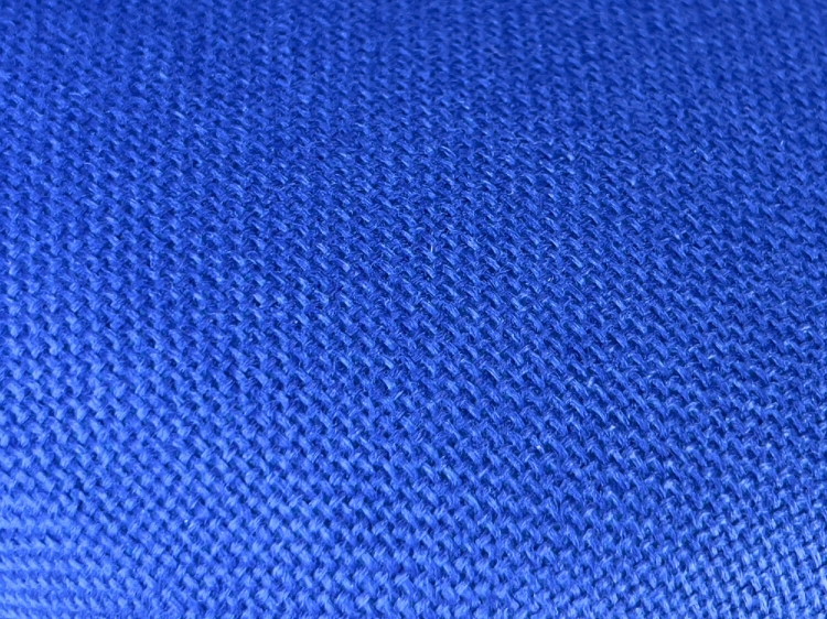 Tapicerka krzesła przemysłowego KRAFFT BLU w intensywnym błękicie, wykonana z teksturowanego materiału. Widoczny detal tkaniny z wyraźnym splotem, idealny do zastosowań w biurach i przestrzeniach roboczych.