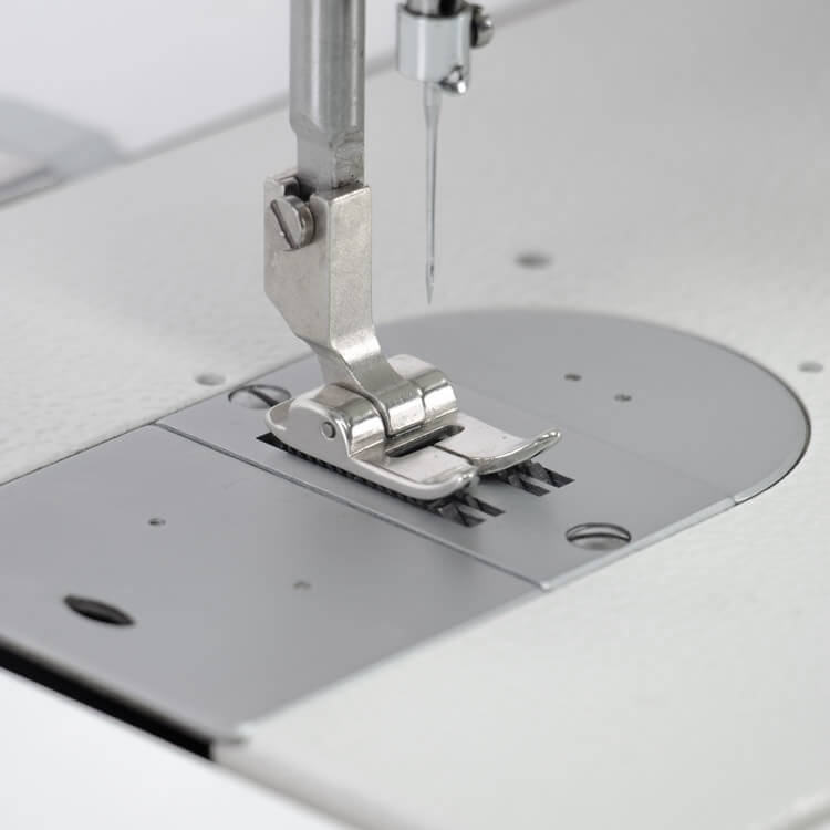 Stopka maszyny do szycia Zygzak ZOJE ZJ20U93-BD, wykonana z metalu, z widocznym igielnikiem. Ujęcie z bliska, pokazujące detale mechanizmu i powierzchnię roboczą. Tło proste, stonowane.