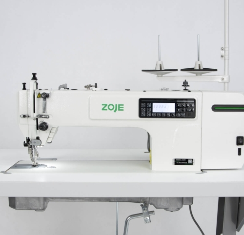Stebnówka ZOJE A0323L-D4 SET w kolorze białym z zielonym logo, widok z boku. Posiada automatyczne funkcje, panel sterujący z wyświetlaczem i przyciskami, oraz dwa stojaki na szpule. Elementy metalowe pod stopką maszyny.