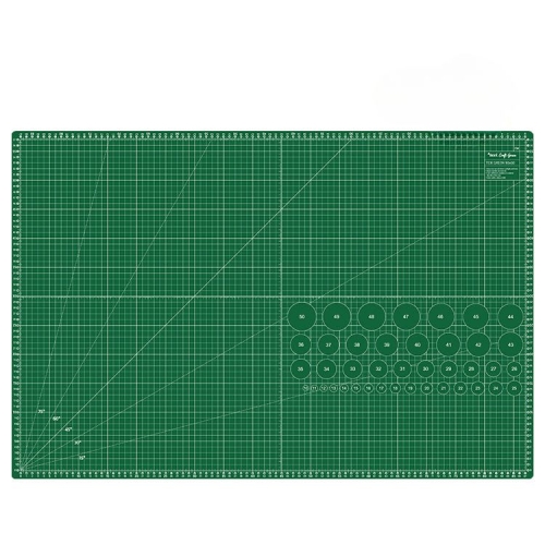 Samoregenerująca mata podkładowa TEXI GREEN w kolorze zielonym, o wymiarach 90x60 cm. Na powierzchni widoczne linie siatki oraz okręgi z numerami, ułatwiające precyzyjne cięcie i pomiar. Ułożona poziomo na białym tle.