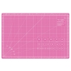 Różowa mata podkładowa TEXI PINK 45x30 cm, samoregenerująca, z siatką w centymetrach oraz kątami, widoczne oznaczenia dla precyzyjnego cięcia, leżąca na prostym tle.