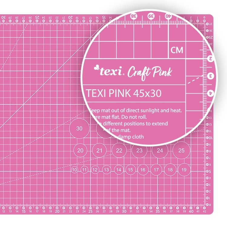 Różowa mata podkładowa TEXI PINK 45x30 cm, samoregenerująca, z siatką pomiarową w centymetrach. Widoczna etykieta z instrukcjami użytkowania oraz oznaczeniami na krawędzi. Ułożona płasko na jasnym tle.