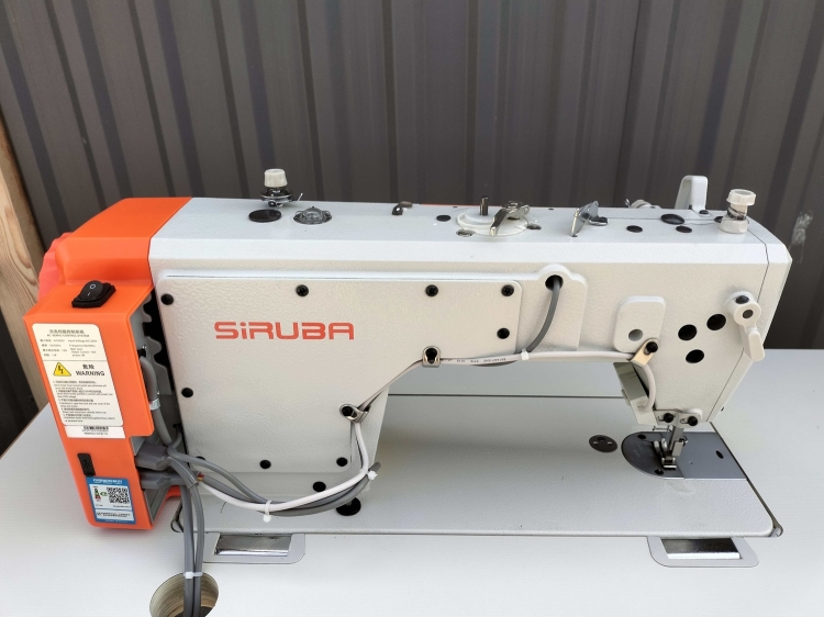 Stebnówka SIRUBA DL720G-BM1 w kolorze białym z pomarańczowymi akcentami, jednoigłowa, z obcinaczem nici. Ujęcie frontalne, widoczna płyta robocza i elementy sterujące. Przeznaczona do szycia lekkich i średnich materiałów.