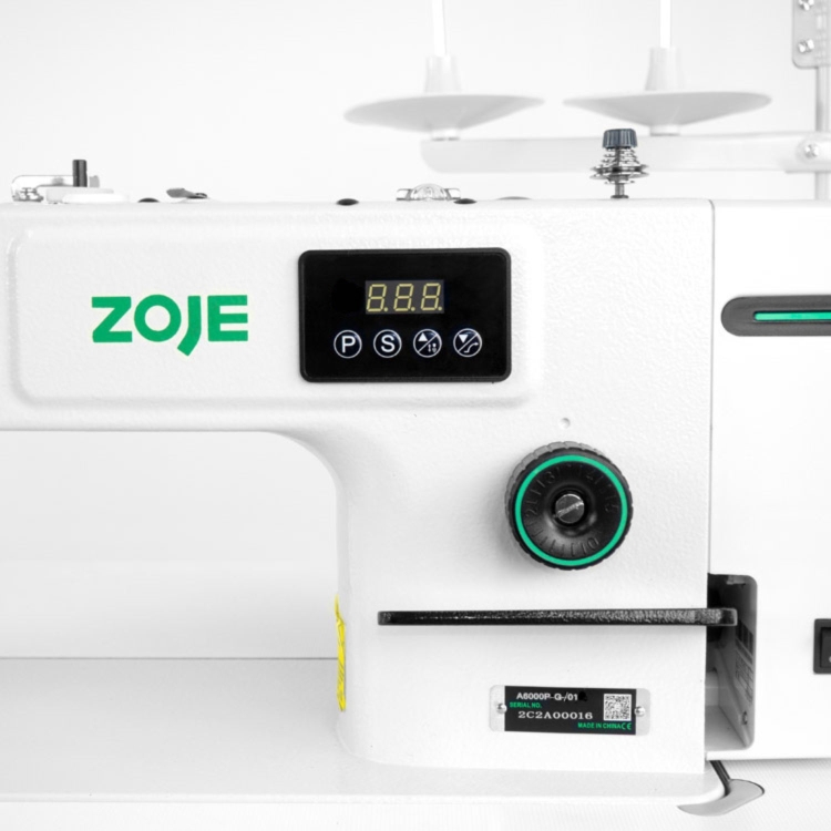 Stebnówka ZOJE A6000P-5G-01, 1-igłowa, z białą obudową. Widoczny panel sterujący z wyświetlaczem LED i przyciskami, pokrętło regulacji. Z tyłu dwa uchwyty na szpule. Obok etykieta z numerem seryjnym i logo ZOJE w zielonym kolorze.