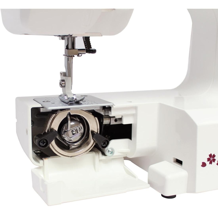 Maszyna do szycia Janome JUNO E1015, widok z boku na mechanizm chwytacza. Kolor biały, z metalowym chwytaczem umieszczonym w dolnej części. Widać również igłę i płytkę z oznaczeniami. Prosta konstrukcja, idealna dla początkujących krawcowych.