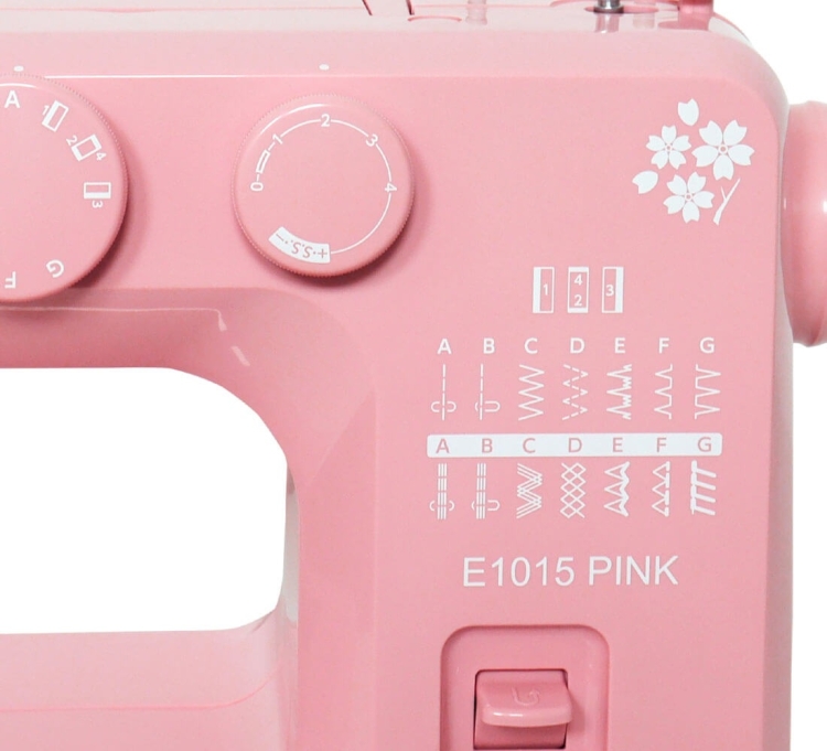 Maszyna do szycia Janome JUNO E1015 w kolorze różowym, z pokrętłami do ustawiania ściegów oraz listą dostępnych wzorów. Widoczny napis E1015 PINK i kwiatowy wzór dekoracyjny. Produkt z prostokątnym otworem na igłę, ustawiony frontalnie.