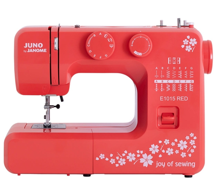 Maszyna do szycia Janome JUNO E1015 w kolorze czerwonym z białymi kwiatowymi zdobieniami. Ujęcie frontalne, widoczna igła, pokrętła do ustawień oraz różne wzory ściegów. Produkt leży na gładkiej powierzchni, z logo joy of sewing na obudowie.
