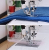 Maszyna do szycia Janome HD 523 EASY JEANS z widoczną stopką do szycia grubszych materiałów, takich jak dżins. Ujęcie z boku prezentuje również szycie na siateczce. Tło w neutralnych kolorach, z kolorowymi szpulkami nici w tle.