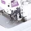 Owerlok TEXI QUATTRO 3F PREMIUM EX, przemysłowy, automatyczny, 4-nitkowy, zbliżenie na stopkę i mechanizm szycia. Widoczne elementy: metalowa płyta, igły, prowadniki, kolorowe nici. Ujęcie z boku, z wyraźnym detalem konstrukcji.