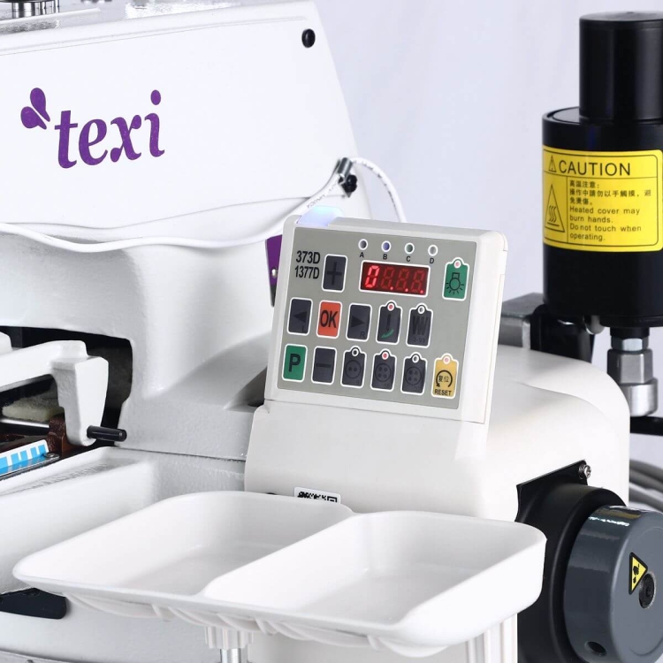Guzikarka TEXI XF PREMIUM EX, elektroniczna, z białą obudową, zawiera panel sterujący z wyświetlaczem LED i przyciskami funkcyjnymi. Widoczne są dwa pojemniki na guziki oraz oznaczenia na obudowie. Tło jasne, neutralne.
