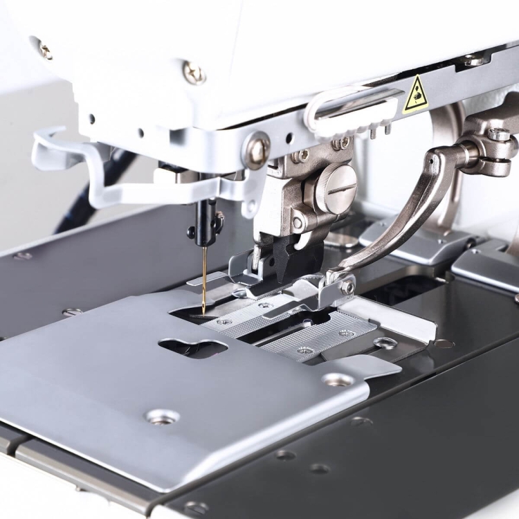 Dziurkarka TEXI QF PREMIUM EX, widok z bliska na mechanizm, metalowa płyta z otworem, igła w pozycji gotowości, elementy sterujące i mocujące, precyzyjny mechanizm do wykańczania odzieży.