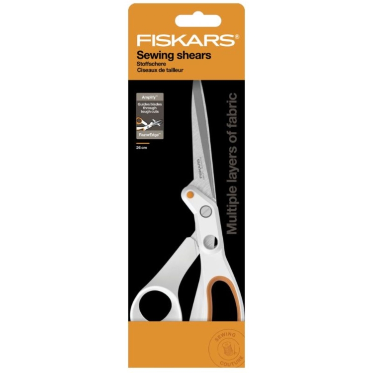 Nożyce krawieckie Fiskars Amplify 1070082 o długości 25 cm, z metalowymi ostrzami i ergonomicznym uchwytem w kolorze białym z pomarańczowymi akcentami, umieszczone na tle opakowania z informacją o możliwości cięcia wielu warstw materiału.