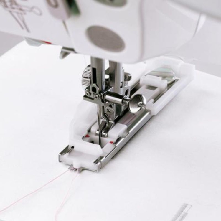 Stopka do automatycznego obszywania dziurek Janome, rotacyjna, o szerokości 7 mm, z metalowym mechanizmem i białą obudową. Ujęcie z bliska, pokazujące stopkę w pozycji roboczej z widocznymi czerwonymi znacznikami na podstawie.