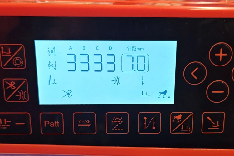 Przemysłowa stebnówka Siruba DL8000-BX2-16Q wyróżnia się nowoczesnym wyglądem i wygodną obsługą. Model ma biały korpus, pomarańczowy panel elektroniczny, wyświetlacz LCD oraz przejrzysty układ przycisków funkcyjnych.