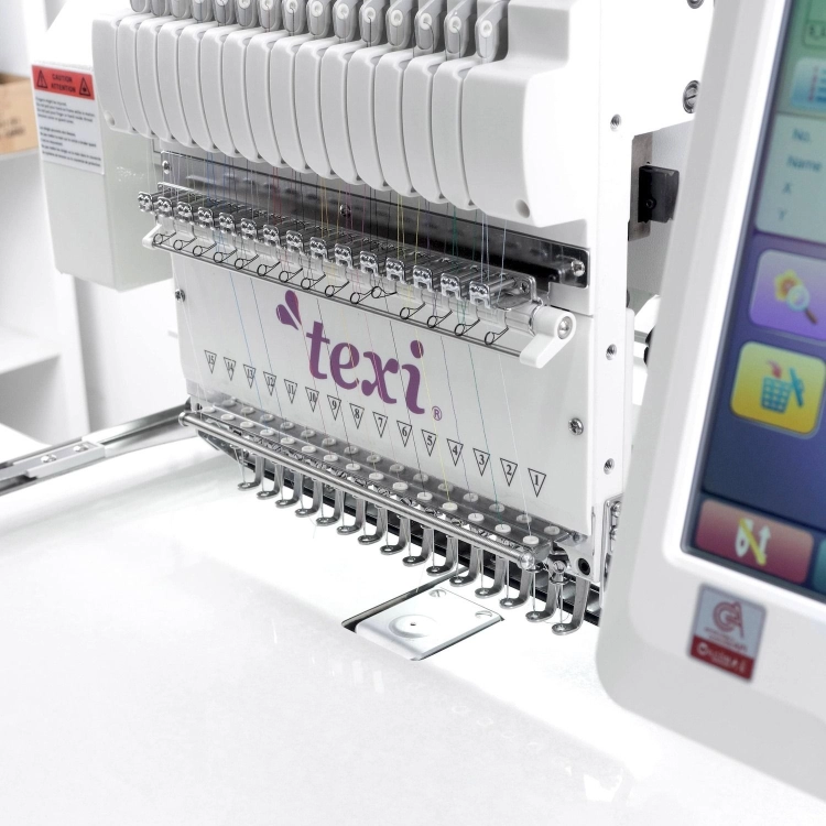 Hafciarka TEXI 1501 XL TS PREMIUM SET, 15-igłowa, widok z boku. Widoczne igły, kolorowe nici oraz panel sterujący. Logo texi na przedniej części maszyny. Maszyna umieszczona na białym tle, w bliskim ujęciu.