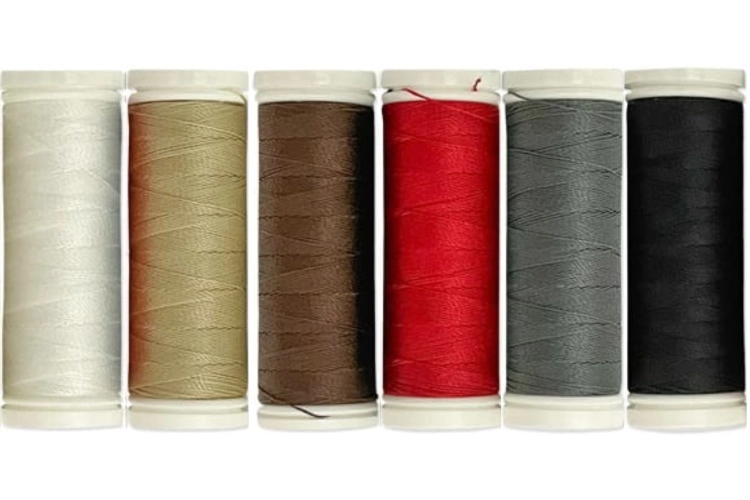 Zestaw 6 nici do szycia skóry Ariadna Leather Tytan 60E/120m, w tym kolory: brązowy, czarny, czerwony, khaki, beżowy i szary. Szpule stoją w rzędzie, każda z widoczną teksturą nici i oznaczeniem koloru.