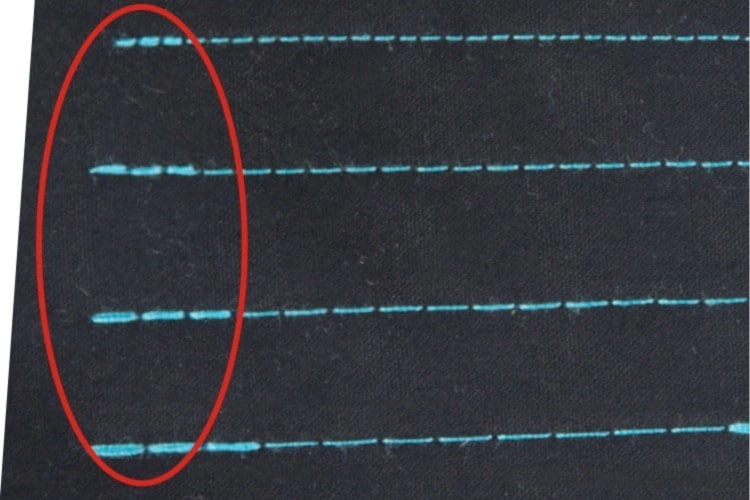 Zbliżenie na ścieg wykonany stebnówką JACK A4B-A-CHL-7, automatyczną jednoigłową maszyną do szycia. Widoczny ścieg w kolorze błękitnym na białym tle materiału, idealny do średnich i ciężkich tkanin.