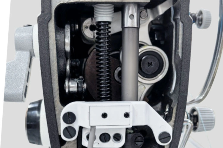 Zbliżenie przedstawia wewnętrzny mechanizm głowicy maszyny JACK. Widoczne są metalowe elementy napędu, wały i połączenia odpowiedzialne za ruch igielnicy oraz prawidłową pracę całego układu szyjącego.
