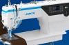 Zdjęcie przedstawia obszar roboczy stebnówki JACK H7 podczas szycia grubszego, brązowego materiału. Dobrze widoczna jest głowica maszyny, panel sterowania oraz miejsce prowadzenia materiału pod stopką.