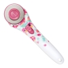 Nóż krążkowy Fiskars Inspiration Flower 1023907 z ostrzem 45 mm, z ergonomiczną rączką w białe kwiaty na różowym tle. Widoczny przycisk blokady i logo Fiskars. Produkt ukazany z boku, leżący na jednolitym tle.