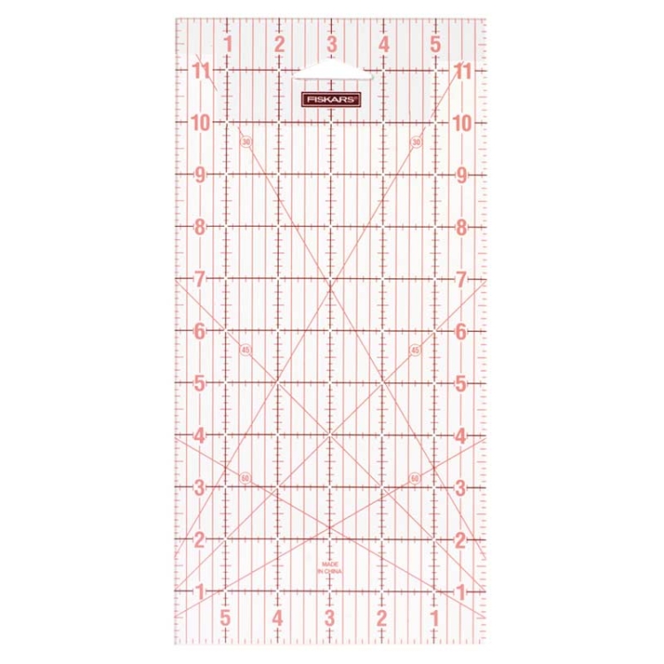 Linijka Fiskars 1004744 do patchworku i quiltingu o wymiarach 150x300 mm, przezroczysta z czerwonymi podziałkami i cyframi, ukazująca kąt 45 stopni. Ujęcie frontalne, linijka leży na białym tle, idealna do precyzyjnego cięcia.