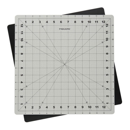 Mata podkładowa Fiskars 1020694 samogojąca, obrotowa, w rozmiarze 350x350x3 mm. W kolorze szarym z siatką w kratkę i oznaczeniami w centymetrach. Widoczna z góry, na tle czarnej maty. Idealna do precyzyjnego cięcia i pracy rzemieślniczej.