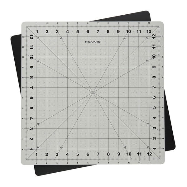 Mata podkładowa Fiskars 1020694 samogojąca, obrotowa, w rozmiarze 350x350x3 mm. W kolorze szarym z siatką w kratkę i oznaczeniami w centymetrach. Widoczna z góry, na tle czarnej maty. Idealna do precyzyjnego cięcia i pracy rzemieślniczej.
