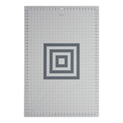 Mata podkładowa Fiskars A1 samogojąca o wymiarach 600x910x2mm, w kolorze szarym, z siatką milimetrową oraz wzorem w formie koncentrycznych kwadratów. Ułożona płasko na jasnym tle.