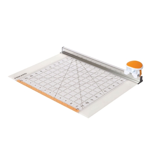 Gilotyna Fiskars 1016264 z obrotowym ostrzem 45 mm, widoczna w pozycji leżącej. Na przezroczystym podłożu znajduje się linijka z oznaczeniami i siatką pomiarową, a także pomarańczowy uchwyt. Tło białe, co podkreśla szczegóły produktu.