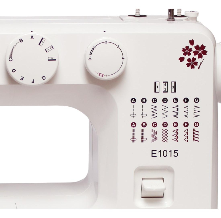 Maszyna do szycia Janome JUNO E1015 w kolorze białym z czerwonymi detalami. Widoczne pokrętła do regulacji oraz tabela ściegów z literami i symbolami. Ujęcie frontalne, zbliżenie na panel sterujący. Wbudowane różne wzory ściegów, przycisk do uruchamiania