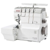 Owerlok Janome AT2000D Professional w kolorze białym, z systemem nawlekania powietrznego. Widoczny stół roboczy, pokrętła do regulacji oraz cztery szpulki z nicią. Maszyna stoi w pozycji otwartej, gotowa do pracy.
