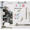 Widok wnętrza owerloka Janome AT2000D Professional, ukazujący mechanizm oraz kolorowe instrukcje obsługi. Widoczne elementy: pokrętło, dźwignie, metalowe części oraz oznaczenia graficzne dotyczące ustawienia nici. Tło białe, proste.