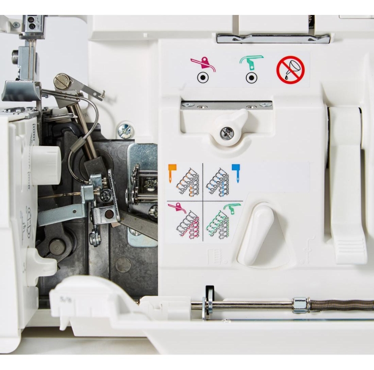 Widok wnętrza owerloka Janome AT2000D Professional, ukazujący mechanizm oraz kolorowe instrukcje obsługi. Widoczne elementy: pokrętło, dźwignie, metalowe części oraz oznaczenia graficzne dotyczące ustawienia nici. Tło białe, proste.