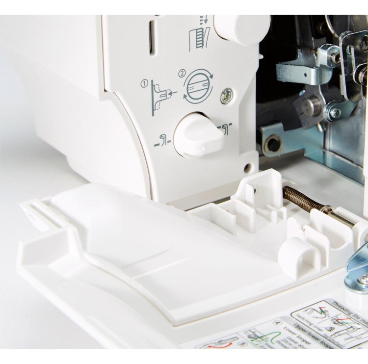 Owerlok Janome AT2000D Professional w kolorze białym, z widocznymi elementami do regulacji oraz instrukcjami na obudowie. Zbliżenie na dolną część maszyny z zamontowanym uchwytem i schematem wprowadzenia nici, co ułatwia użytkowanie.