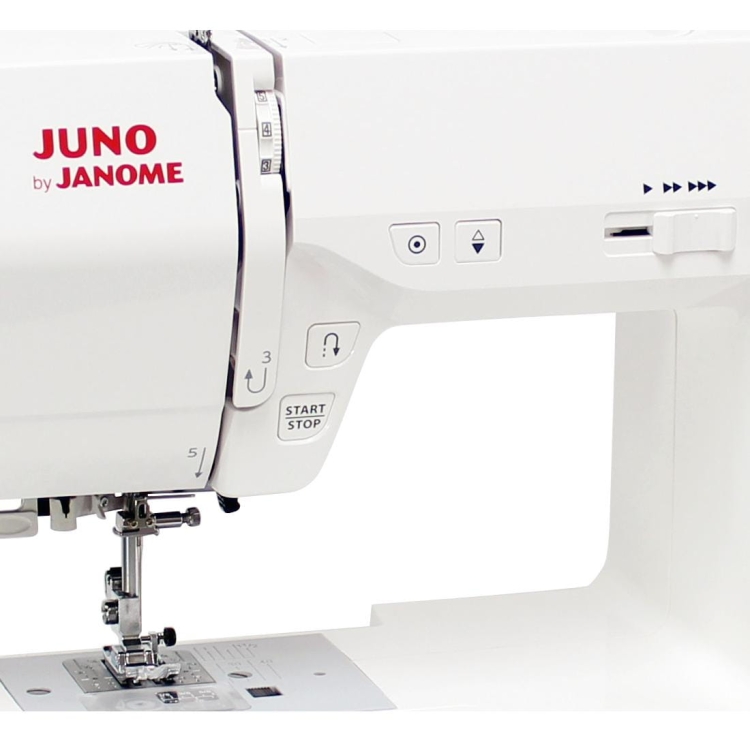 Maszyna do szycia Janome JUNO J30 w kolorze białym, z widocznymi przyciskami, w tym „START/STOP”, pokrętłem wyboru ściegów oraz metalowym stoperem. Ujęcie z boku, pokazujące stół i igłę. Brak dodatkowych elementów w tle.
