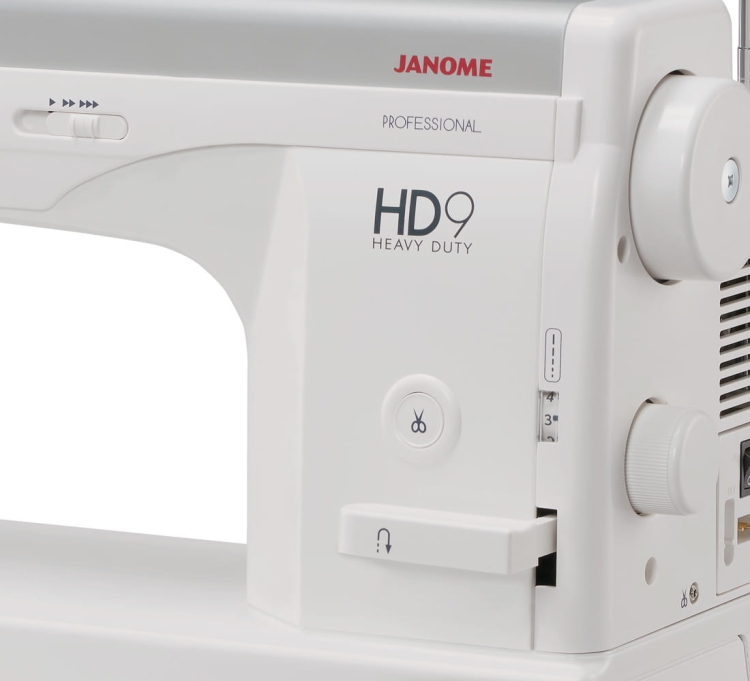 Maszyna do szycia Janome HD9 Heavy Duty w kolorze białym, widok z boku. Na obudowie widoczne logo HD9 Heavy Duty, przyciski cięcia nici oraz regulator długości ściegu. Prosta konstrukcja, idealna do szycia grubszych tkanin.